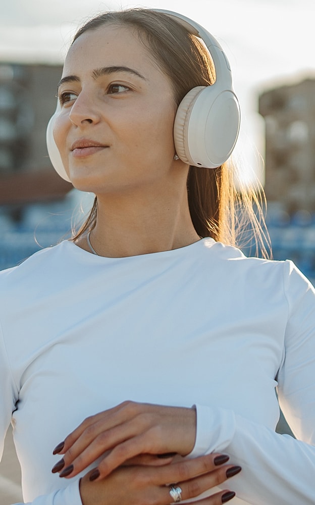Woman wearing headphones outdoors, enjoying music.