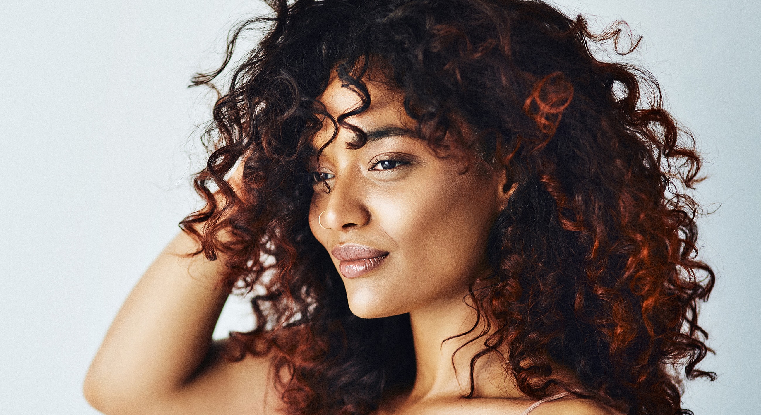 Woman with curly hair smiling softly.