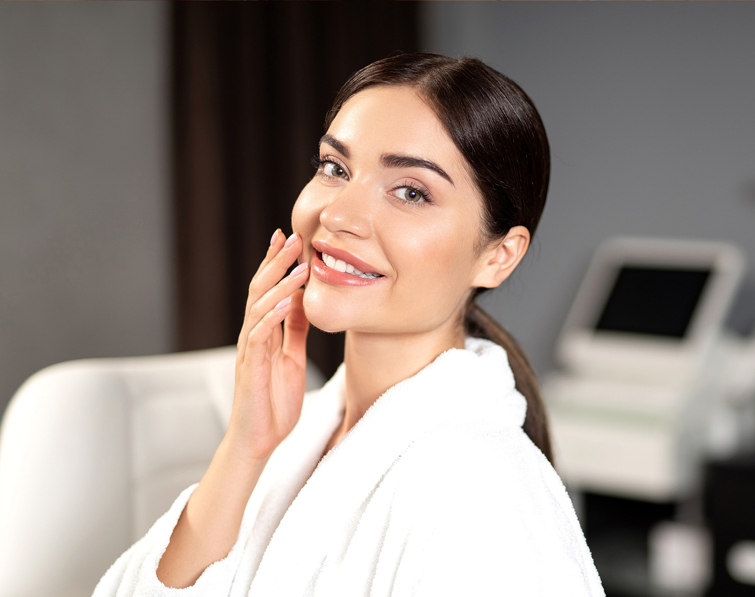 Smiling woman in a spa robe, skincare setting.
